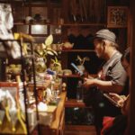 Suasana meja bar di Dongeng Kopi Dalangan saat pengunjung memesan kopi di kedai yang hangat dan remang pada malam hari.