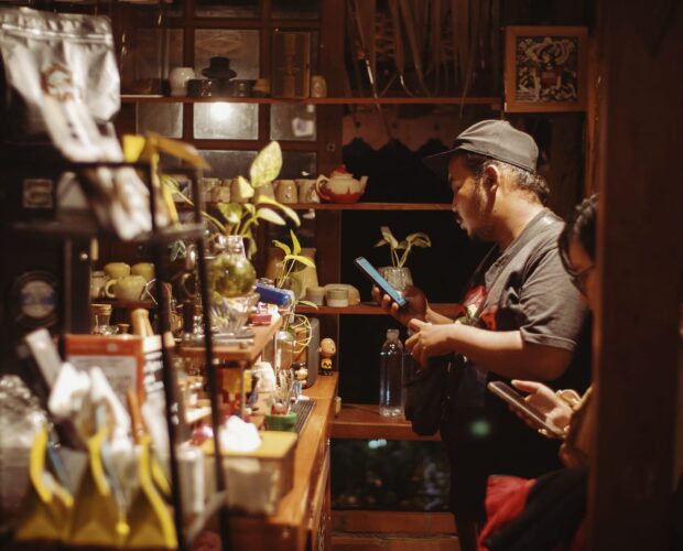 Suasana meja bar di Dongeng Kopi Dalangan saat pengunjung memesan kopi di kedai yang hangat dan remang pada malam hari.