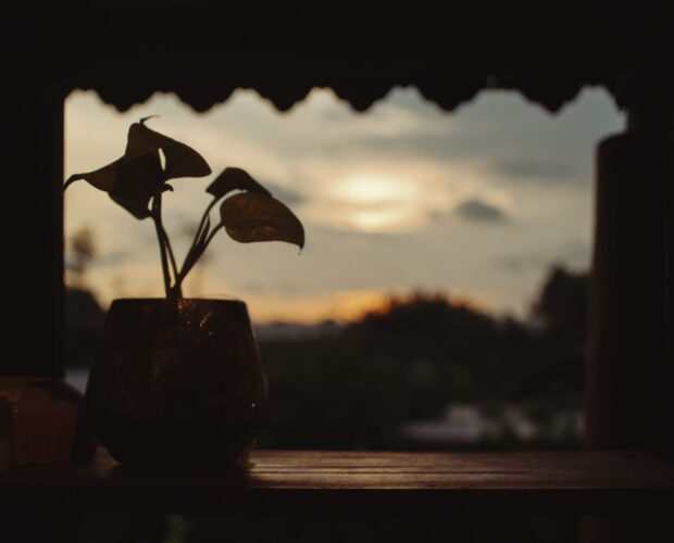 Secangkir kopi di meja saat langit senja berwarna lembayung.