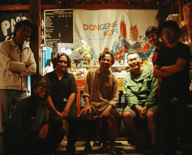 Sebuah kamera dan secangkir kopi di meja Dongeng Kopi, simbol mengabadikan momen di kedai kopi untuk melawan lupa.