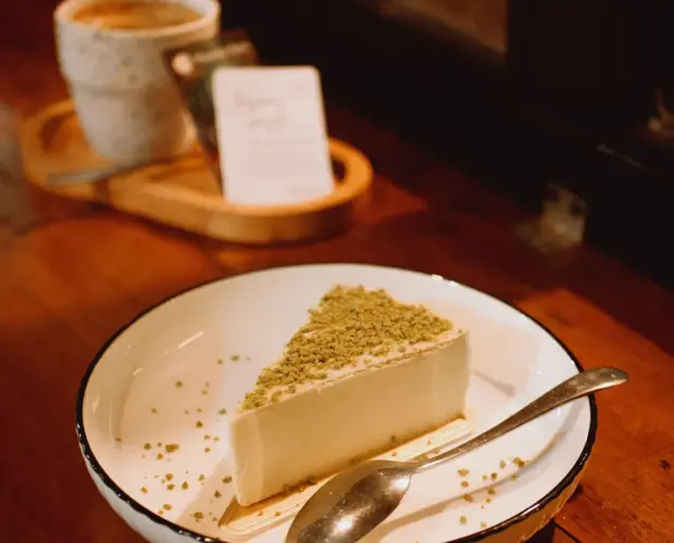 Secangkir kopi hitam dan kue keju sebagai menu pendamping kopi di Dongeng Kopi Dalangan Sleman.