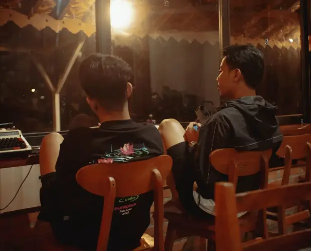 "Dua orang duduk di depan meja Dongeng Kopi, tempat ngopi yang tenang di Sleman untuk ruang obrolan dan curhat."